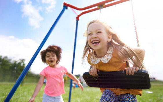 A little girl laughing while on a swing after a pediatric dental appointment